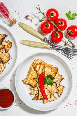 Fried slices Pleurotus eryngii mushrooms with sauce, spices and herbs. Healthy vegan food concept, hard light, dark shadowwhite plaster background, flat lay, top view