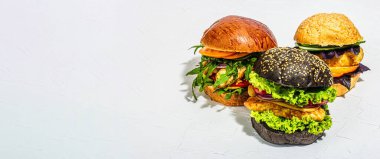 Set of homemade fish burgers. Fresh ingredients, ripe vegetables, fast food concept. Trendy hard light, dark shadow, wooden stand, white putty background, banner format