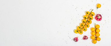 Culinary background with ripe vegetables. Yellow tomato cherries, garlic and sesame seeds. Fresh vegetables on white putty background, modern hard light, dark shadow, flat lay, banner format