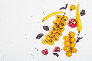 Culinary background with ripe vegetables. Yellow tomato cherries, chili pepper, garlic, purple basil. Fresh vegetables on white putty background, modern hard light, dark shadow, flat lay, top view