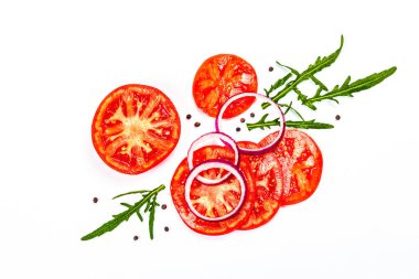 Assorted fresh vegetables and spices isolated on white background. Ripe tomato slices, purple onion, arugula and black peppercorn. Traditional ingredients for cooking healthy food, top view