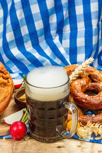 Traditional Oktoberfest set. Pretzels, beer, weisswurst, smoked pork knuckle eisbein with fermented cabbage and mustard. German festival food concept. Old wooden background, copy space