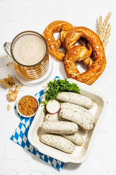 Traditional Oktoberfest set. Pretzels, beer, weisswurst with mustard. German festival food concept. Trendy hard light, dark shadow, white putty background, top view