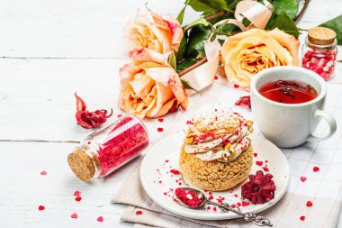 Romantik çay kavramı. Fransız Shu keki, amber çayı, bir buket gül, şenlikli dekor. Sevgililer Günü konsepti, Kadınlar Günü 8 Mart, Düğün. Beyaz tahta arkaplanı, kapat