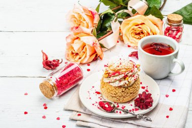 Romantik çay kavramı. Fransız Shu keki, amber çayı, bir buket gül, şenlikli dekor. Sevgililer Günü konsepti, Kadınlar Günü 8 Mart, Düğün. Beyaz tahta arkaplanı, kapat