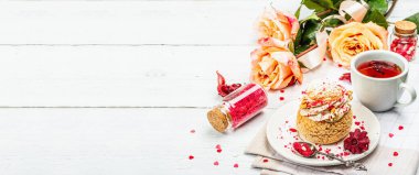 Romantik çay kavramı. Fransız Shu keki, amber çayı, bir buket gül, şenlikli dekor. Sevgililer Günü konsepti, Kadınlar Günü 8 Mart, Düğün. Beyaz pano arkaplanı, pankart biçimi