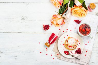 Romantik çay kavramı. Fransız Shu keki, amber çayı, bir buket gül, şenlikli dekor. Sevgililer Günü konsepti, Kadınlar Günü 8 Mart, Düğün. Beyaz tahta arka planı