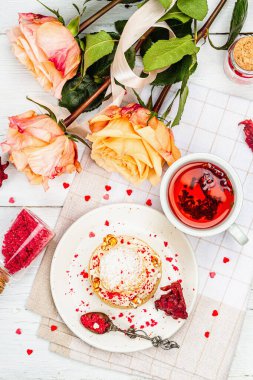 Romantik çay kavramı. Fransız Shu keki, amber çayı, bir buket gül, şenlikli dekor. Sevgililer Günü konsepti, Kadınlar Günü 8 Mart, Düğün. Beyaz tahta arkaplan, üst görünüm
