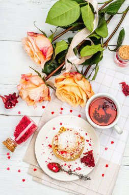 Romantik çay kavramı. Fransız Shu keki, amber çayı, bir buket gül, şenlikli dekor. Sevgililer Günü konsepti, Kadınlar Günü 8 Mart, Düğün. Beyaz tahta arkaplan, üst görünüm