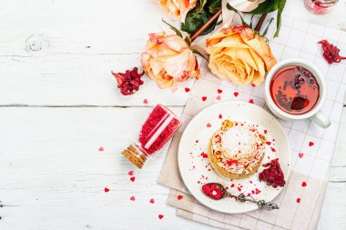 Romantik çay kavramı. Fransız Shu keki, amber çayı, bir buket gül, şenlikli dekor. Sevgililer Günü konsepti, Kadınlar Günü 8 Mart, Düğün. Beyaz tahta arkaplan, üst görünüm