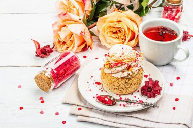 Romantik çay kavramı. Fransız Shu keki, amber çayı, bir buket gül, şenlikli dekor. Sevgililer Günü konsepti, Kadınlar Günü 8 Mart, Düğün. Beyaz tahta arkaplanı, kapat