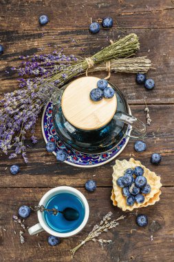 Kır çayı konsepti. Lavanta çiçekleri ve yabanmersini. Vintage düzenleme, sert ışık, karanlık gölge, ahşap arka plan, üst görünüm