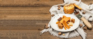 Kurabiye ve fındıklı Norveç kahvaltısı. Sağlıklı yemek ve yemek, kahvaltı için organik malzeme. Geleneksel İskandinav kahverengi peyniri, ahşap arka plan, rustik tarz, pankart biçimi