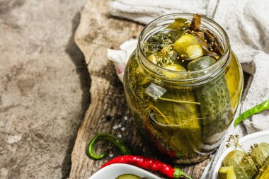 Kış organik gıdalar için salatalık turşusu. Bir kavanoz ev yapımı turşu, temiz yemek, vejetaryen konsepti. Modaya uygun sert ışık, koyu gölge, gri beton arkaplan, kopyalama alanı