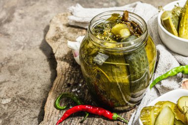 Kış organik gıdalar için salatalık turşusu. Bir kavanoz ev yapımı turşu, temiz yemek, vejetaryen konsepti. Modaya uygun sert ışık, koyu gölge, gri beton arkaplan, kopyalama alanı