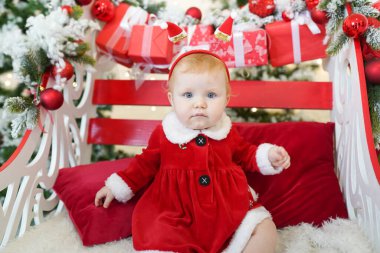 Noel ağacı ve hediyelerin yanında Noel Baba gibi giyinmiş kız çocuğu, yeni yıl tatilinde.