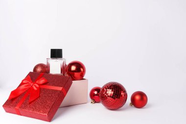 Beyaz arka planda kırmızı hediye kutusu, dekorasyon, şablon ve kopyalama alanı olan bir şişe Noel kadını parfümü.