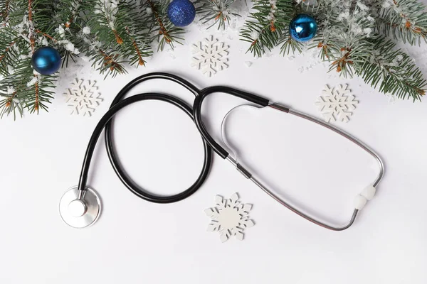 Sağlık sektöründe Noel 'i kutluyoruz. Süslü steteskop ve beyaz arkaplanda kar taneleri