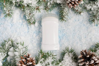 Kış kozmetik ürünleri terlemeyi engelliyor. Mavi arka planda Noel ağacı ve kar var. Vücut bakımı kavramı.