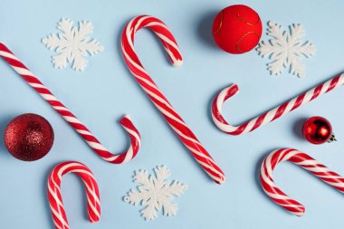 Mavi arka planda, kar taneleri ve kırmızı süslemeli mutlu Noeller. Düz yatıyordu