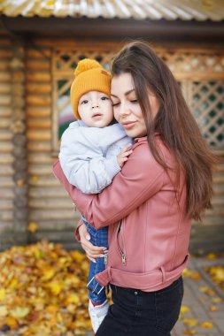 Mutlu aile annesi ve çocuğu Sonbahar parkında yürüyorlar