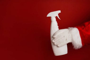 Noel Baba, kırmızı arka planda bulaşık deterjanı ile bulaşık deterjanı tutuyor.