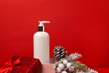 Kozmetik ürün losyonu ya da hediye kutusunda Noel arkaplanında köknar ağacıyla birlikte duş jeli. Kış vücut bakım ürünleri