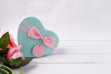 Sevgililer Günü için üzerinde pembe kurdele ve beyaz ahşap masa üzerinde kağıt etiket olan hediye kutusu. Boşluğu kopyala