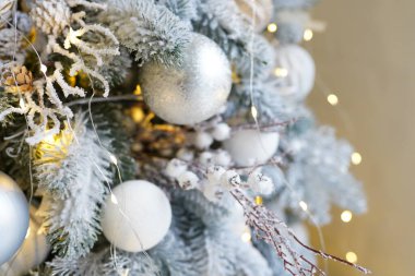 Noel ağacında Noel süslemeleri. Beyaz ve gümüş toplar dallara parlayan lambalar karla serpiştiriliyor. Yeni yıl için şenlikli geleneksel kusursuz arka plan