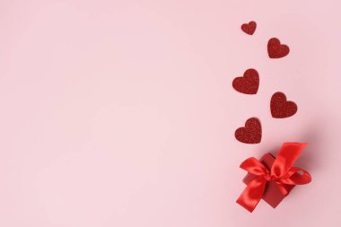 Pembe sevgililer günü arka planında kırmızı kalpler olan hediye kutusu, yıldönümü, anneler günü ve doğum günü selamı, kopyalanmış uzay