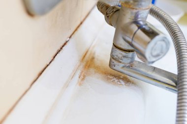 Pas lekeleri, kireç boyası ve banyoda musluğu olan eski kirli lavabo, su musluğu..
