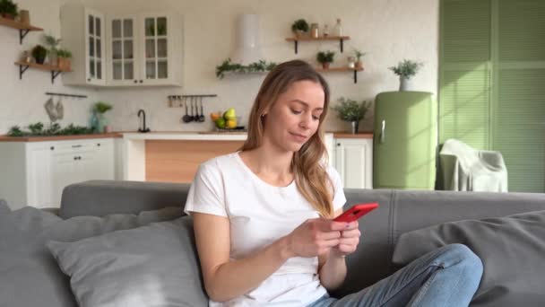 Bonne Jeune Femme Vérifiant Les Médias Sociaux Tenant Smartphone Maison — Video