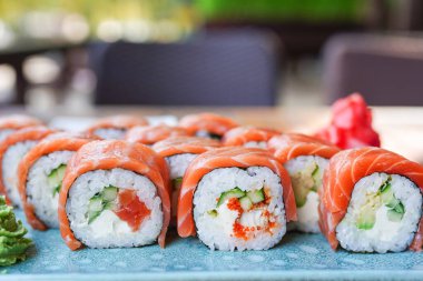 Philadelphia usulü suşi, somon, füme yılan balığı, avokado, kafede mavi tabakta krem peynir. Suşi menüsü. Japon yemeği.