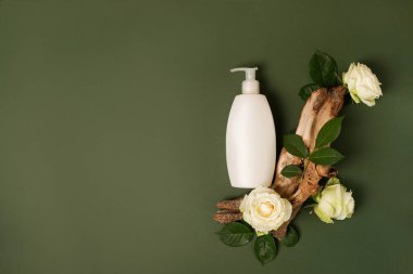 Cilt kremi, şampuan, ahşap ve çiçeklerle kaplı yeşil arka planda saç kremi için makyaj şişesi. Doğal güzellik ürünü.