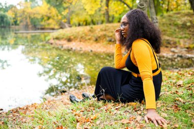 Çekici kıvırcık saçlı, koyu tenli kadın. Keyfi yerinde. Hafta sonu açık havada sonbahar parkında.
