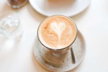 Kafedeki beyaz masada kalbi olan bir fincan kahve.