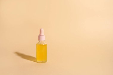 Işık arka planında gölgesi olan kozmetik yağ şişesi. Yatay model, afiş, poster, kopyalama uzayı. Sarı serum, özüt, emülsiyon, eko losyon.