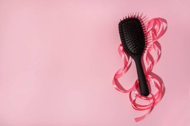 Pembe kurdeleli tarak fırçası ve kopyalama alanı olan pembe arkaplan üzerindeki gölge