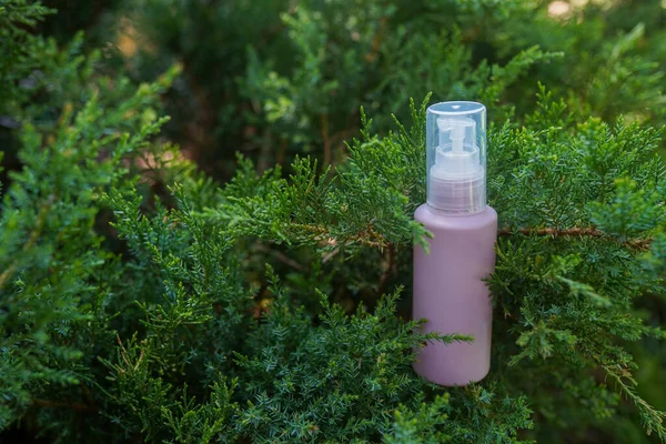 Purple cosmetic bottle with serum, essential oil or other skin care product in forest outdoors. Natural Organic Spa Cosmetic Beauty concept. mockup