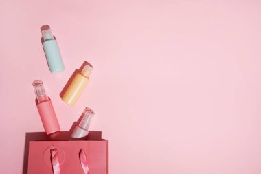 Kozmetik ürünleri için pembe arka planda fotokopi alanı olan renk şişeleri