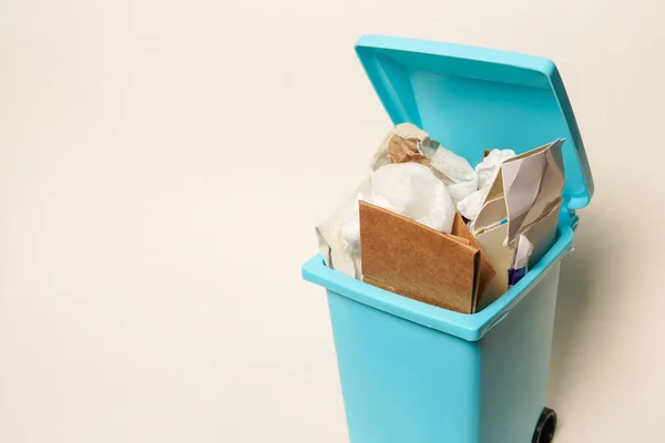 Over full paper trash can on white background with copy space