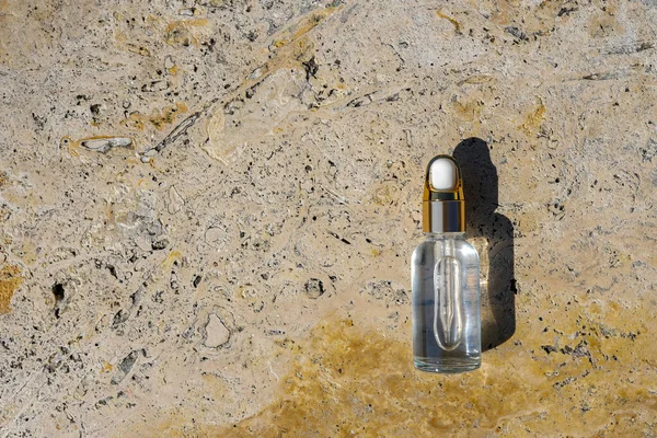 Amber glass cosmetic bottle with serum or essential oil on concrete background. Skincare cosmetic. Beauty concept