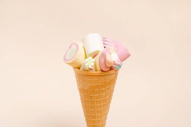 Colorful marshmallows with icecream cone on light background with copy space. Creative minimal sweet holiday concept