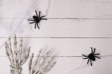 İskelet eller ve örümcek ağıyla Cadılar Bayramı beyaz ahşap arka planı, kopyalama alanı, düz yatış