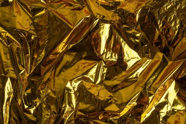 Crumpled foil texture background, close up golden foil