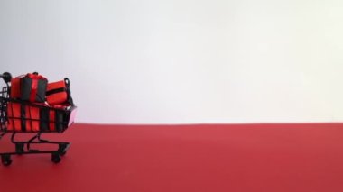 Beyaz arka planda siyah ve kırmızı hediye kutuları olan alışveriş arabası. Kara Cuma, alışveriş ve kutlama konsepti