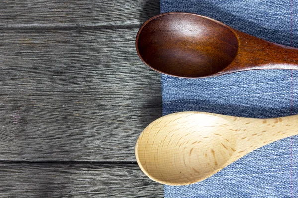 Wood background and spoon on blue jeans texture. — Stock Photo, Image