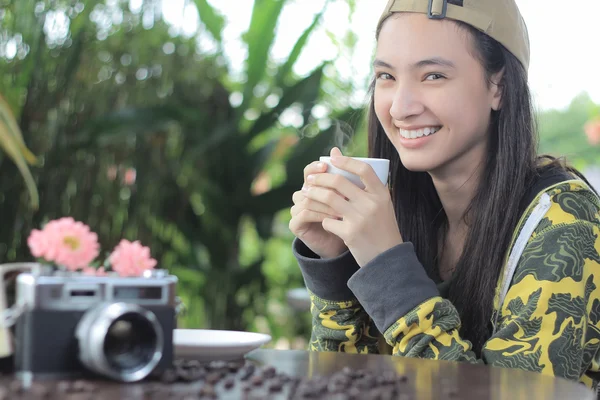 Kobieta trzyma kubek kawy uśmiechający się w kawiarni — Zdjęcie stockowe