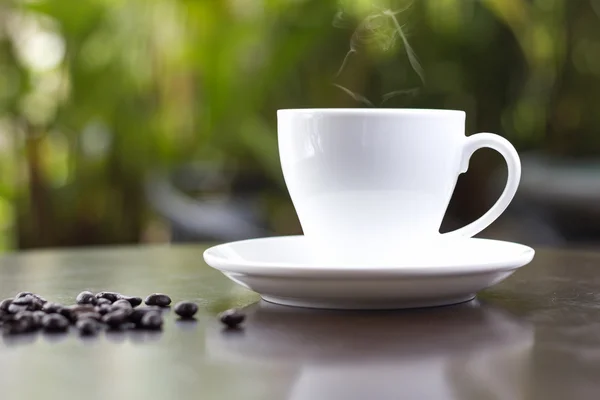 Чашка свіжої кави з кавовими зернами на дерев'яному столі — стокове фото