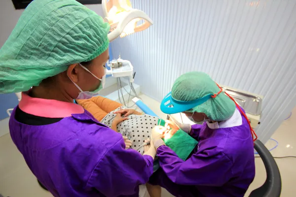 Dentista infantil tratar los dientes de bebé debajo con curado dental Imágenes De Stock Sin Royalties Gratis